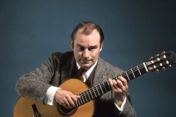 classical guitarist julian bream playing guitar looking at camera