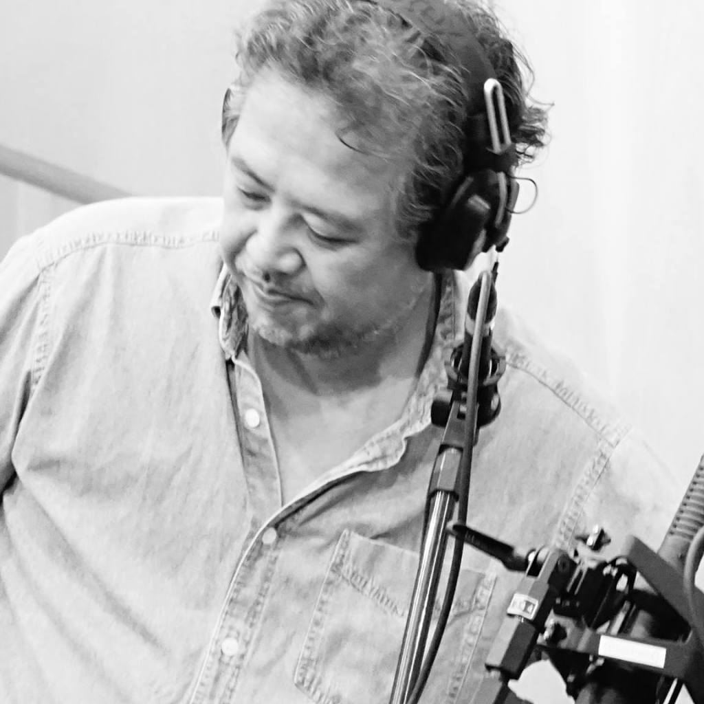 Recording engineer Ricardo Marui wearing headphones in front of a microphone