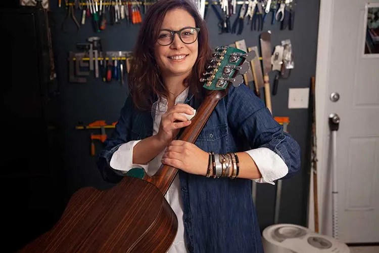 Luthier Rachel Rosenkrantz polishes an acoustic guitar neck