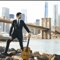 Pablo Sainz-Villegas on the river banks beneath a bridge with classical guitar