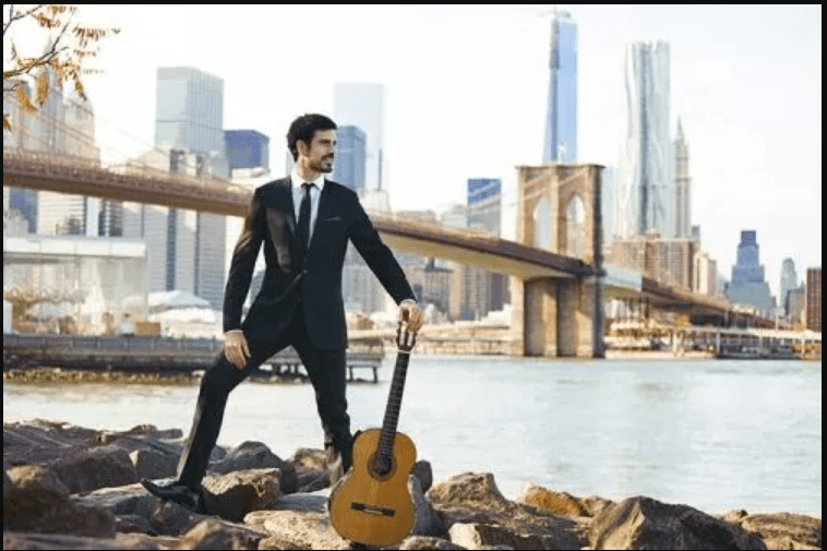 Pablo Sainz-Villegas on the river banks beneath a bridge with classical guitar