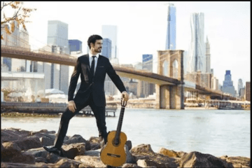 Pablo Sainz-Villegas on the river banks beneath a bridge with classical guitar